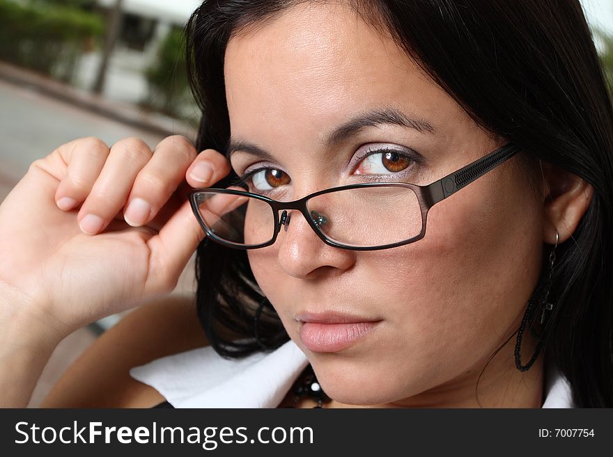 Young woman pulling down her glasses to reveal her beautiful brown eyes. Young woman pulling down her glasses to reveal her beautiful brown eyes