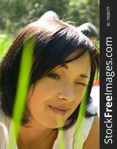 Beautiful young girl on a field among fresh green grass