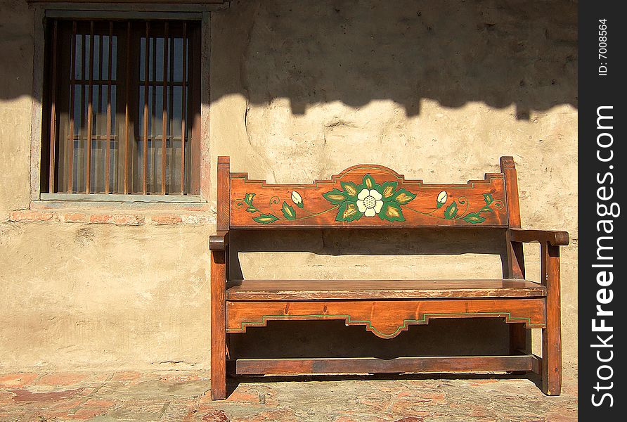 Old painted bench sit in an exterior corridor at Mission San Juan Capistrano, California.