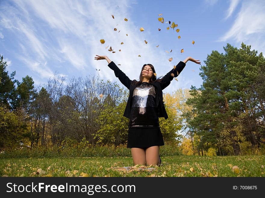 Young woman throw autumnal leaves.