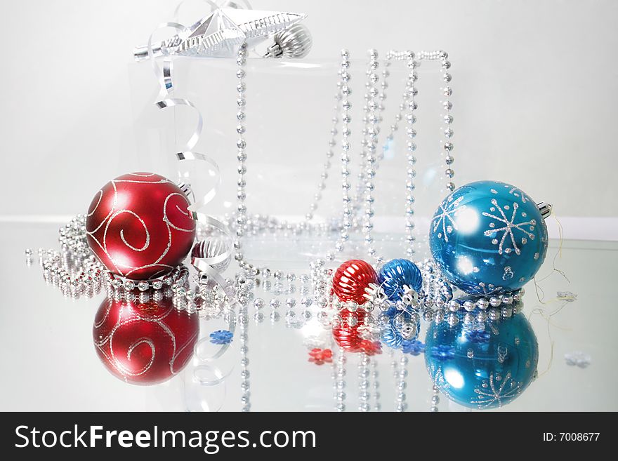 A lovely blue and red baubles on a mirror  surface with ribbons and beads. A lovely blue and red baubles on a mirror  surface with ribbons and beads.