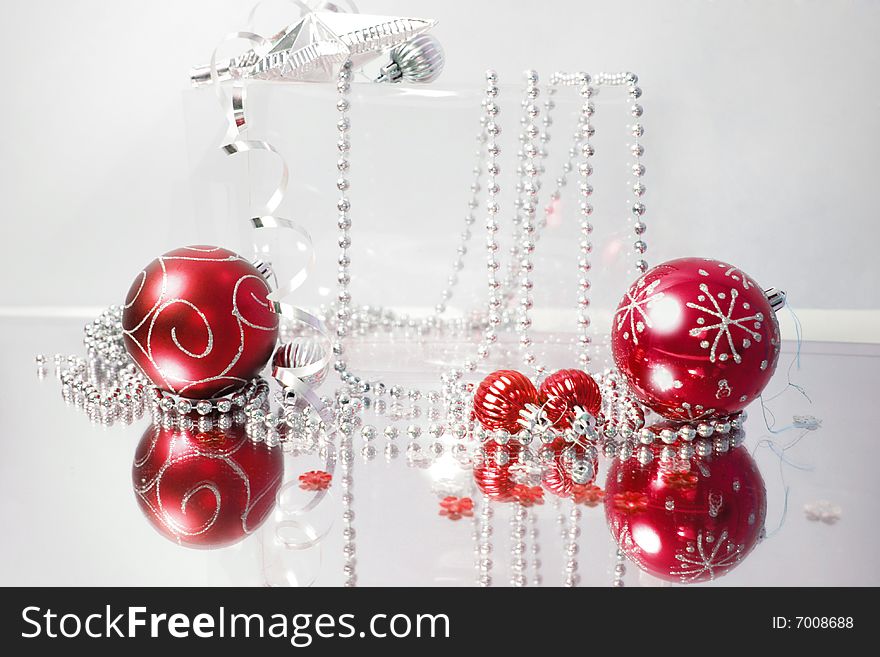 A lovely red baubles on a mirror  surface with ribbons and beads. A lovely red baubles on a mirror  surface with ribbons and beads.