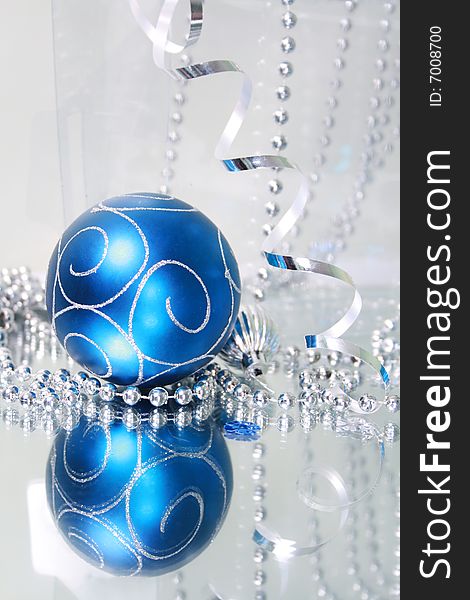 A lovely blue baubles on a mirror  surface with ribbons and beads. A lovely blue baubles on a mirror  surface with ribbons and beads.