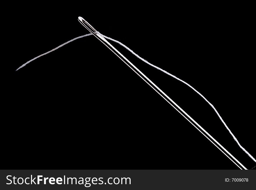 Macro of a needle and white thread on a black background. Macro of a needle and white thread on a black background
