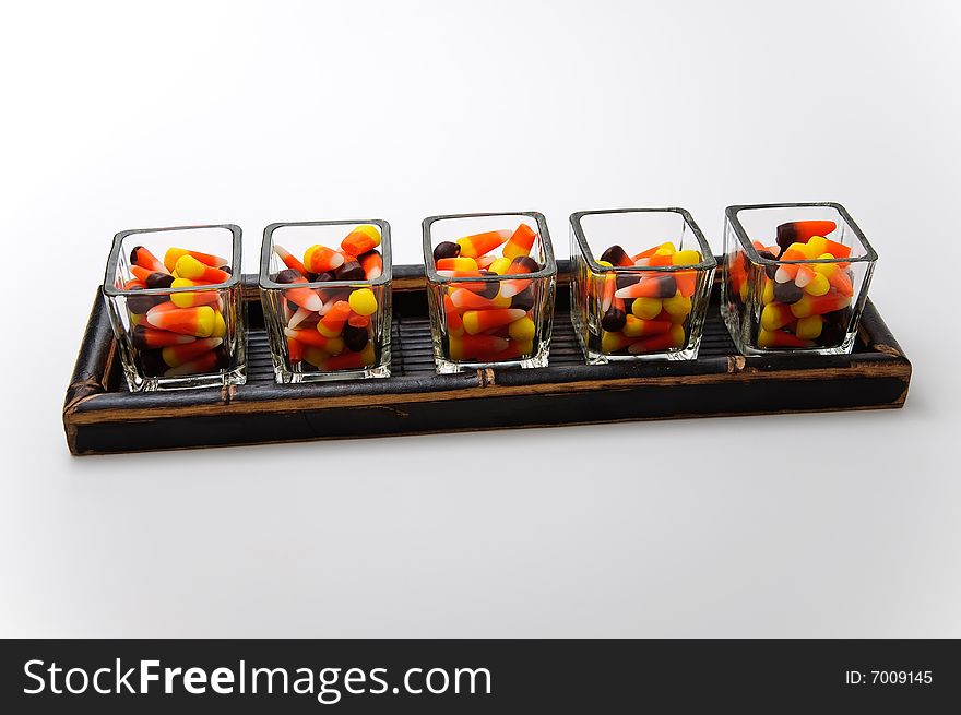 Candy corn in glass holders on a wood tray. Candy corn in glass holders on a wood tray.