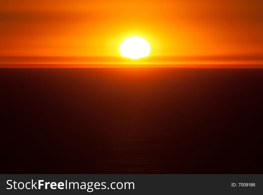 The sun setting over the Pacific Ocean gives a warm, orange glow to the sky. The sun setting over the Pacific Ocean gives a warm, orange glow to the sky.