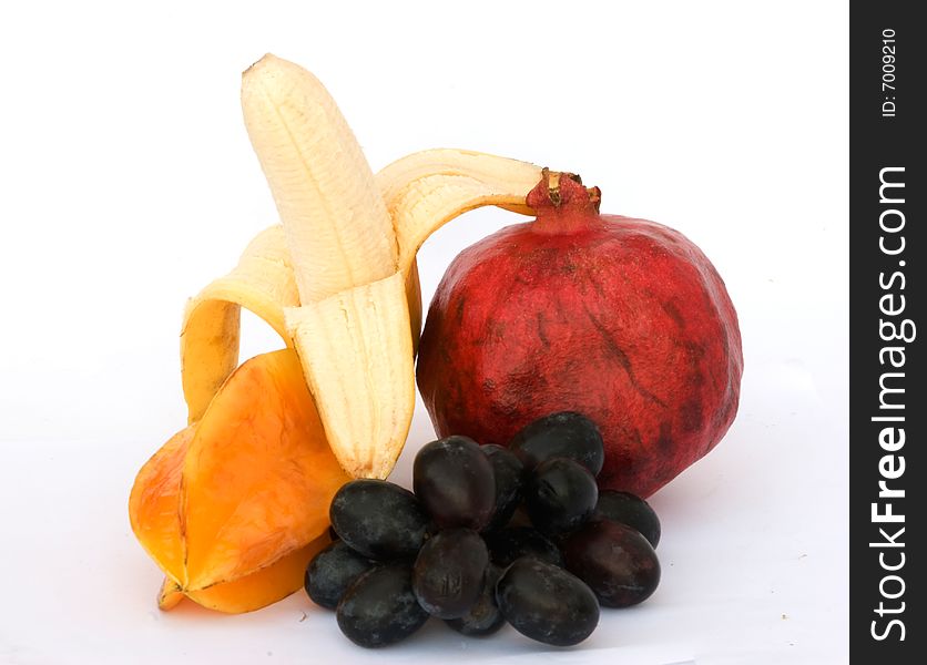 Banana, pomegranate, carambola, and grapes isolated on white background