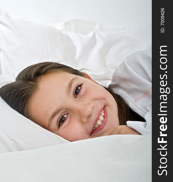 Young girl lying in bed smiling at camera