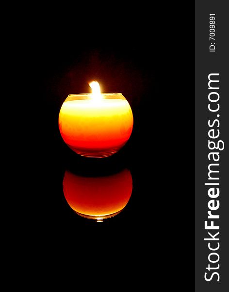 A candle with black background reflected