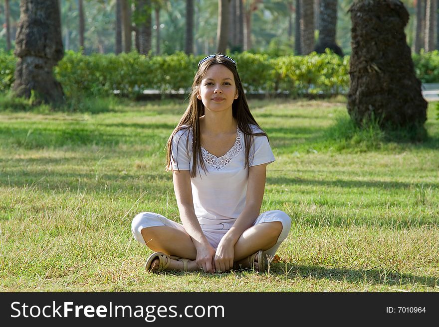 Beautiful woman sitting in a park on a grass
