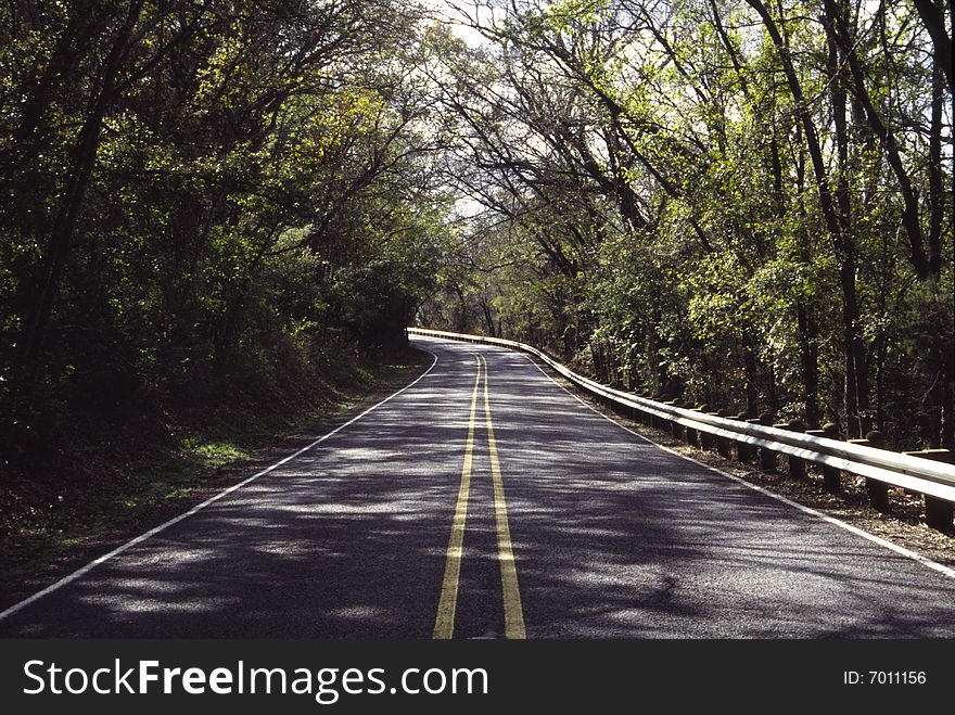 A lonely back road through a forest area. A lonely back road through a forest area.