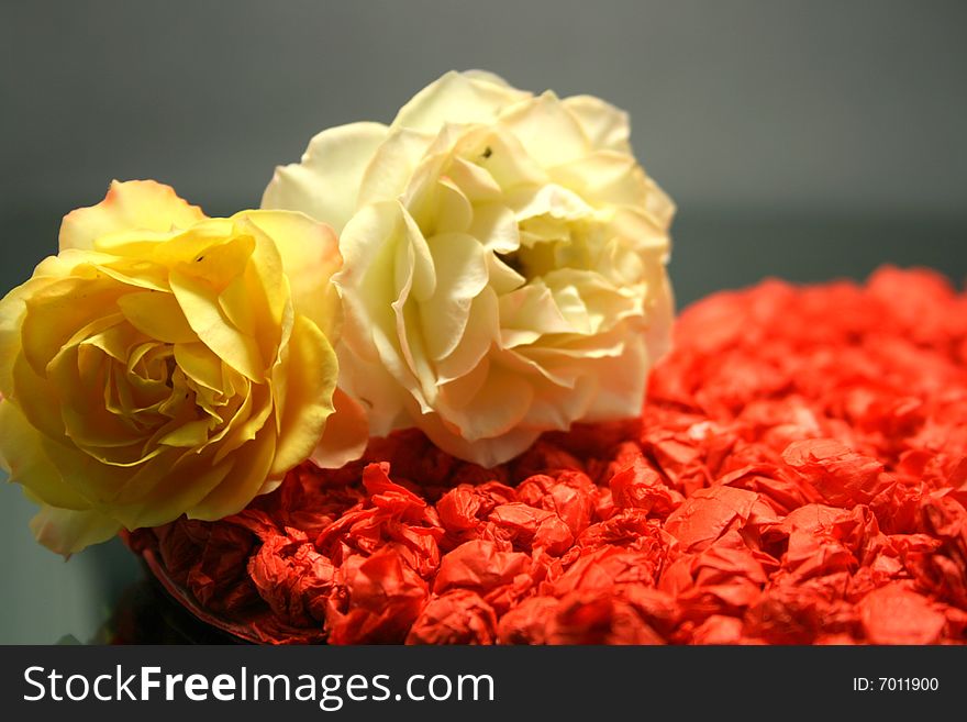 Two yellow roses on a black stage against a red paper heart on background. Two yellow roses on a black stage against a red paper heart on background