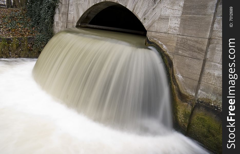 Small waterfall under a bridge in the English Garden, Munich, Germany.