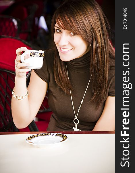 Young smiling woman drinking coffee in an elegant cafe. Young smiling woman drinking coffee in an elegant cafe.