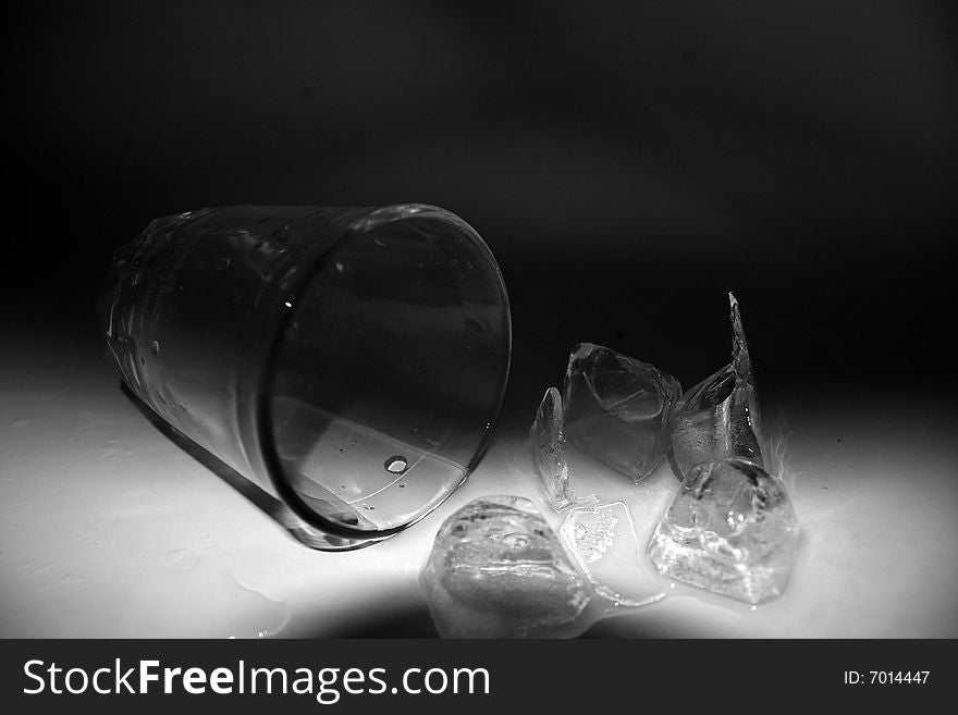 The fallen thick glass tumbler, the poured out ice, water. The fallen thick glass tumbler, the poured out ice, water