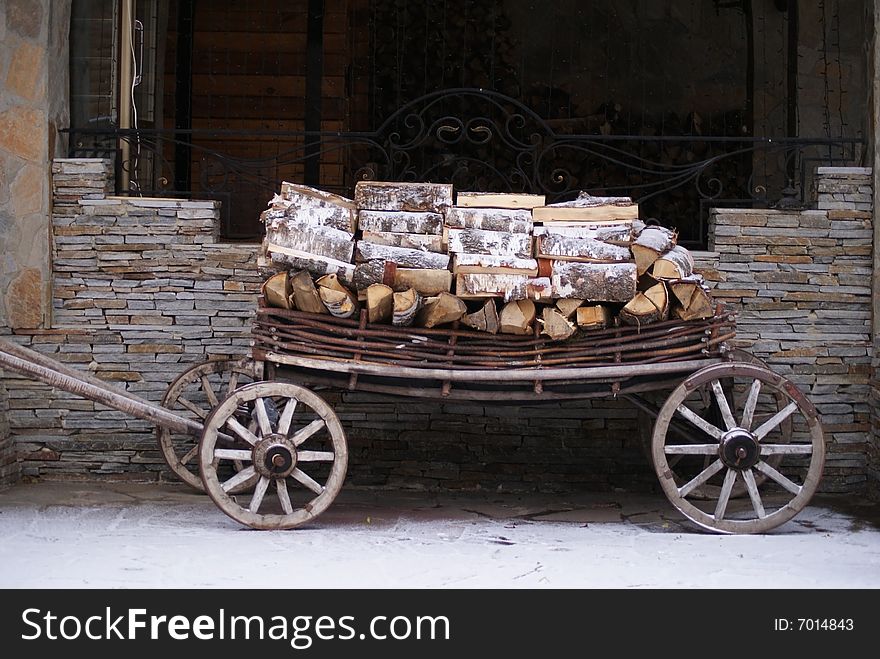 Old cart with wood with stone wall at background
