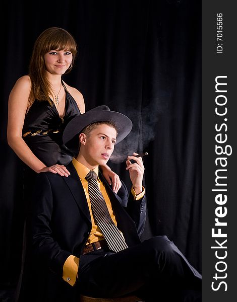 An image of woman and man with cigar in dark room. An image of woman and man with cigar in dark room
