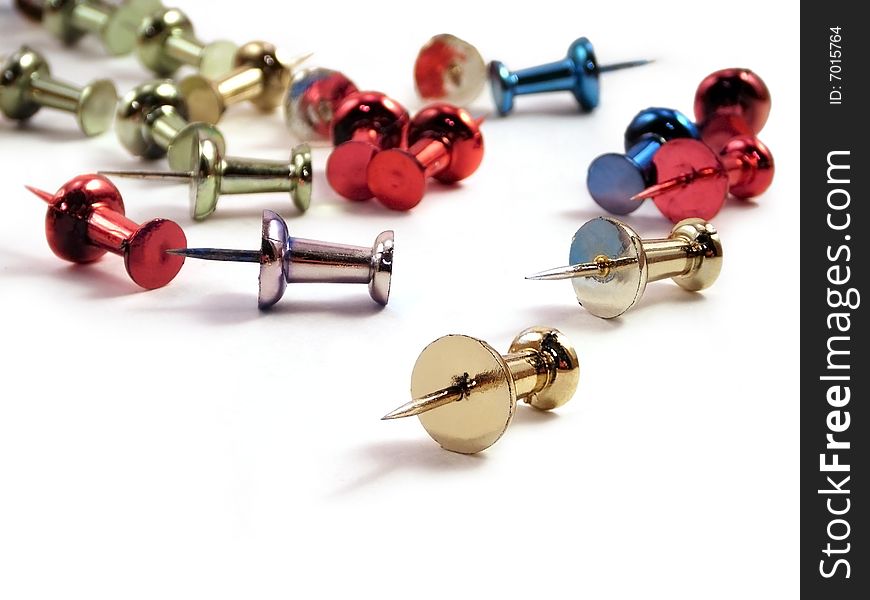 Colored metallic thumb tacks against a white background.