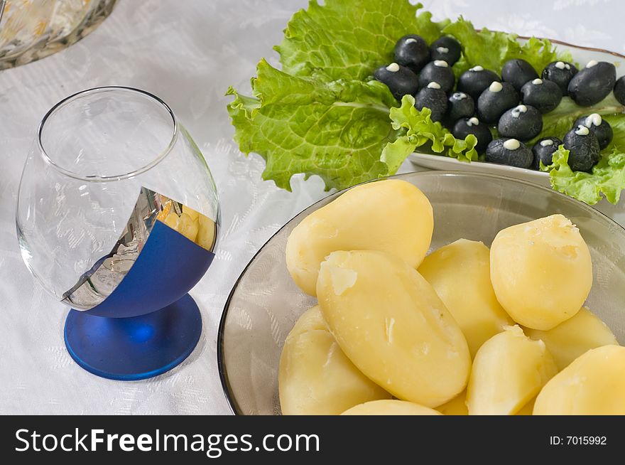 Boiled potato, olives, green lettuce on a table. Boiled potato, olives, green lettuce on a table.