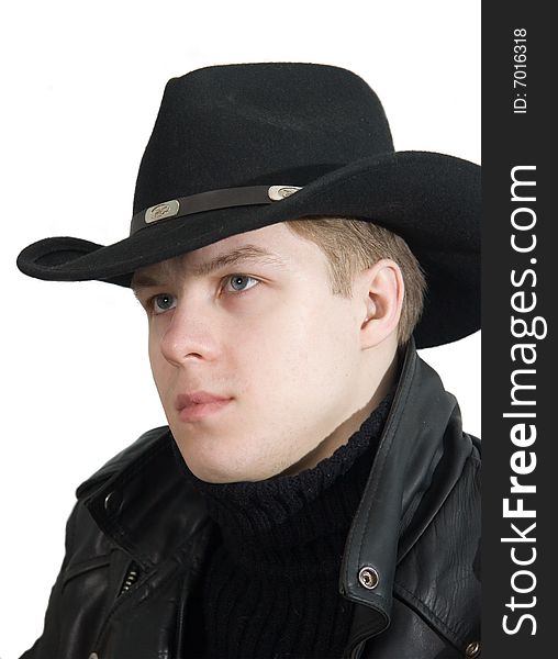 The young man in clothes of black colour sits and looks from below upwards from under a hat. The young man in clothes of black colour sits and looks from below upwards from under a hat