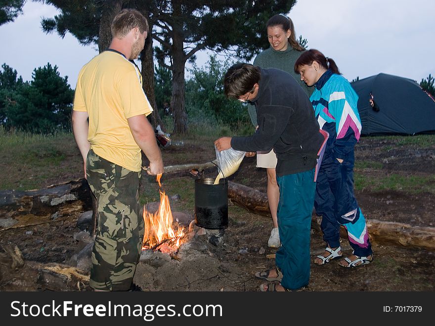 Hikers cook millet porridge on bonfire. Hikers cook millet porridge on bonfire
