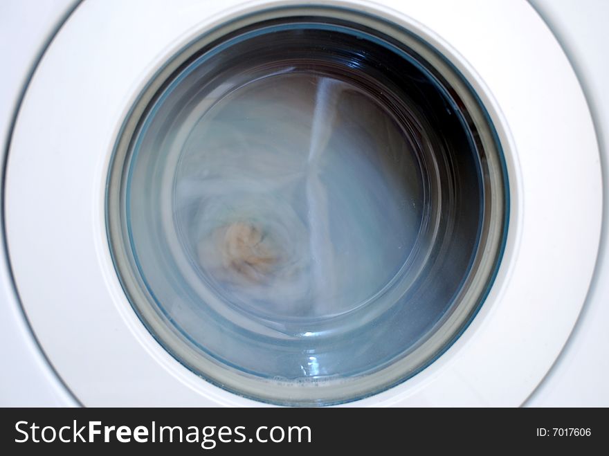 Close up of a washing machine. The drum is spinning and the contents blurred. Close up of a washing machine. The drum is spinning and the contents blurred