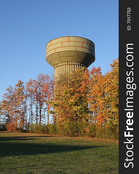 A water tower under construction behind bright autumn leaves