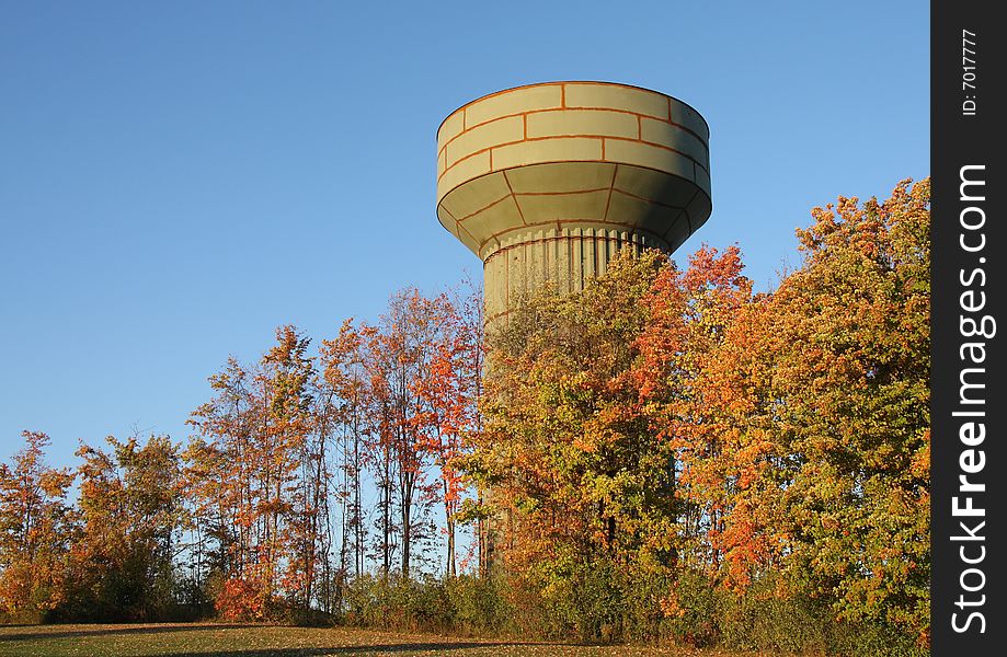 A water tower under construction behind bright autumn leaves