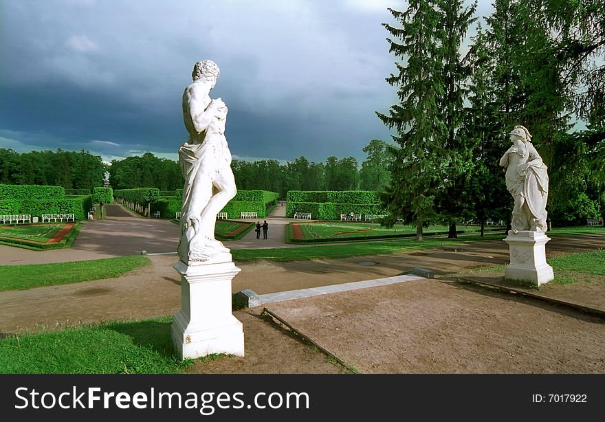 Classical statues in park looking at man and woman