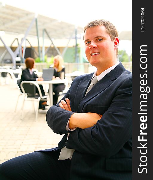 Successful business man hand folded and smiling with two of his associates on the background