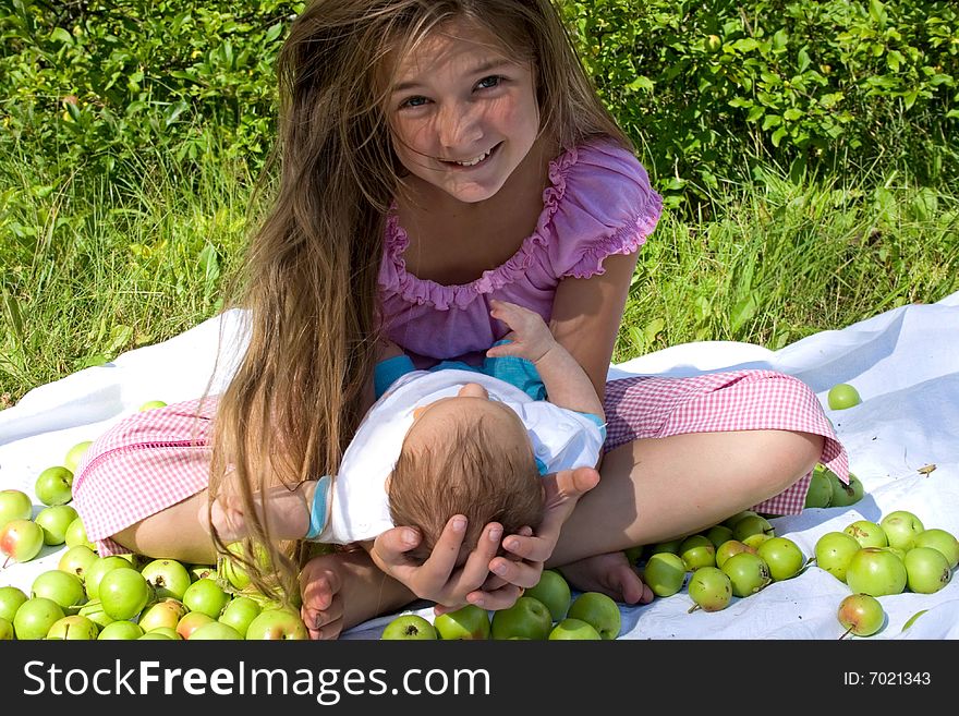 Little girl sitting with her baby brother among apples. Little girl sitting with her baby brother among apples
