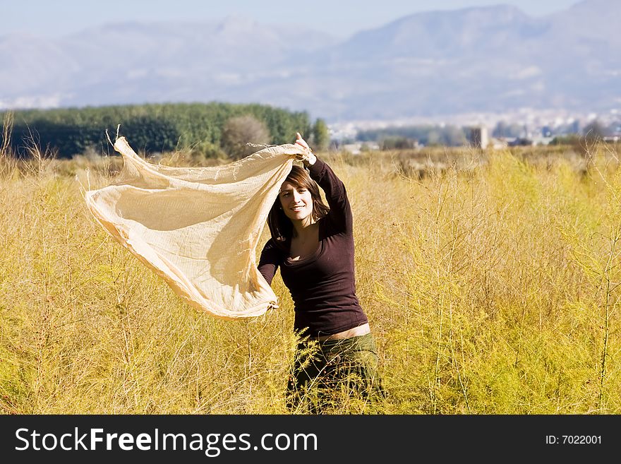 Young woman dancing with scarf in a field. Young woman dancing with scarf in a field.