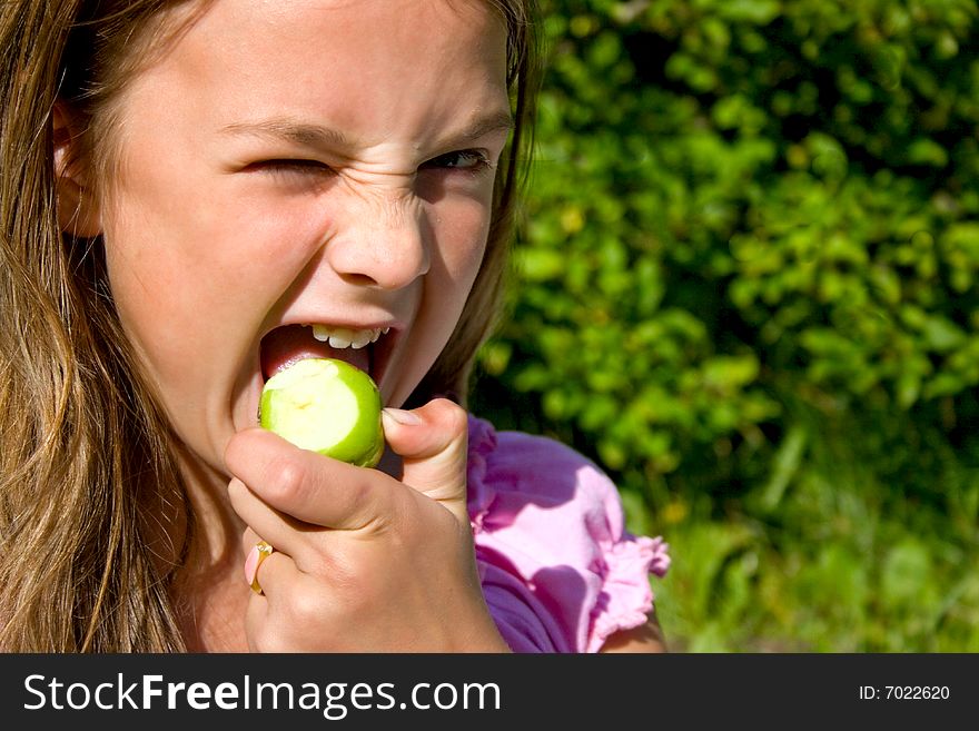 Little girl biting green apple. Little girl biting green apple