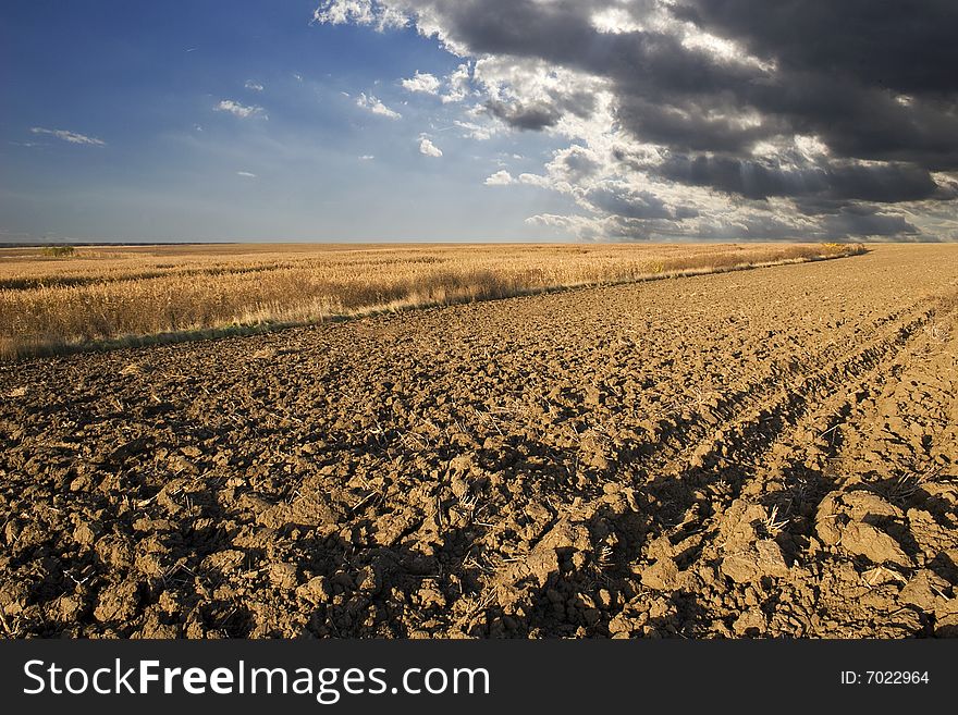 Cultivated ploughland  and stormy clouds in background. Cultivated ploughland  and stormy clouds in background.