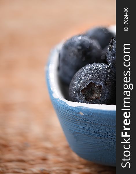 Blueberries in a small blue dish on rustic background, super macro, shallow DOF