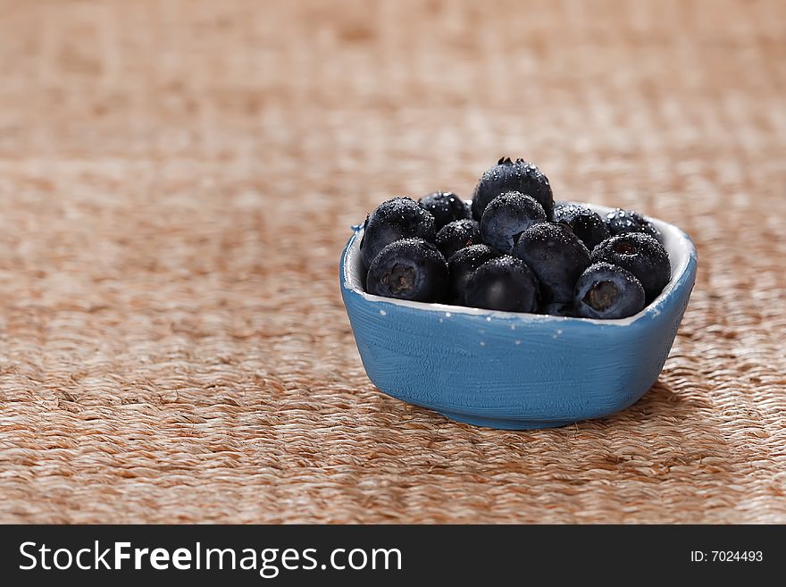 Blueberries in a small blue dish on rustic background, macro, shallow DOF