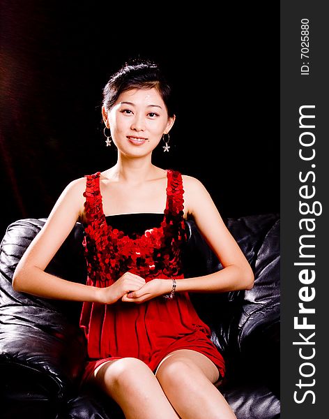 Asian female model in red skirt sitting on sofa. Asian female model in red skirt sitting on sofa