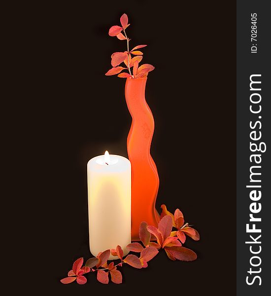 Orange vase on black background with autumn branch and decorative burning candle. Orange vase on black background with autumn branch and decorative burning candle