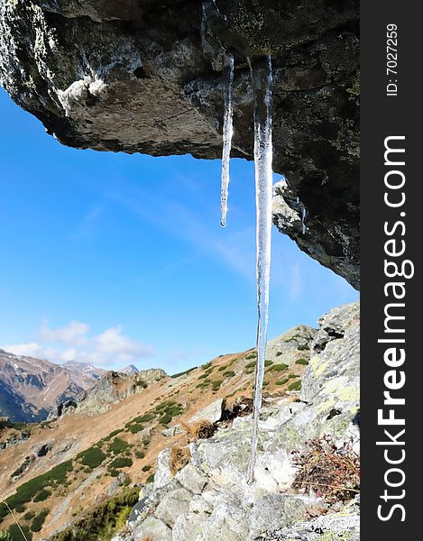 Icicles hanging from rock with mountains in background