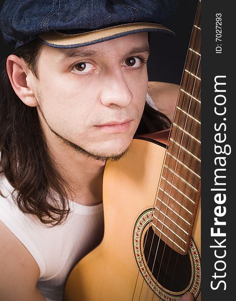 Cheerful man in cap with guitar on black