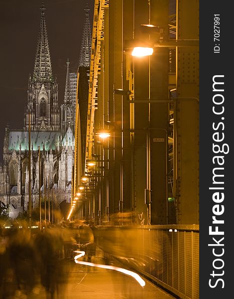 Dom in Cologne with arcs of Hohenzollern bridge, shadows of people walking on the bridge and bycycle light track. Dom in Cologne with arcs of Hohenzollern bridge, shadows of people walking on the bridge and bycycle light track.