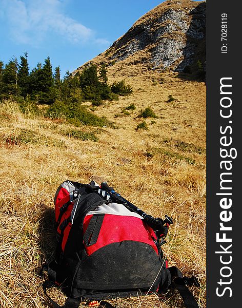 Red backpack on yellow grass with mountains on the background