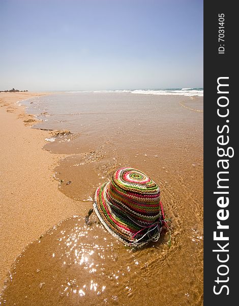 Colored sun hat on water edge on deserted beach. Colored sun hat on water edge on deserted beach