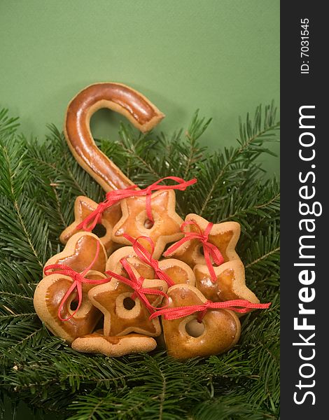 A pile of gingerbread cookies nestled in nest of fir branches and isolated on green paper. A pile of gingerbread cookies nestled in nest of fir branches and isolated on green paper