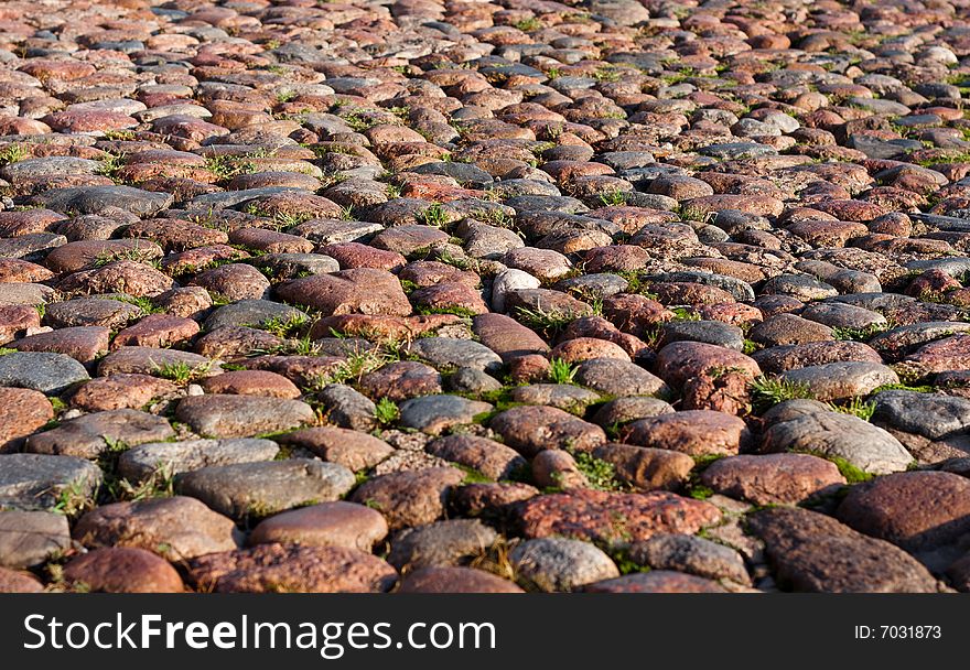 Granite roadway with a grass making the way between stones. Granite roadway with a grass making the way between stones