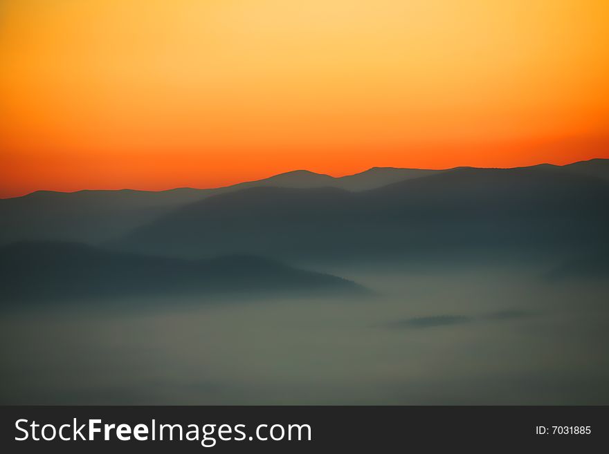 An image of a sunrise in mountains. Mist in a valley