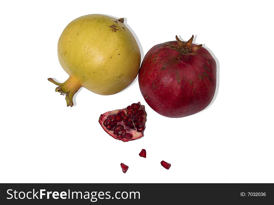 Two isolated red and yellow pomigranates and their small grainy and juicy piece