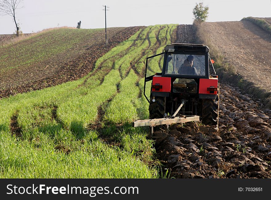 Red-black tractor working on a field