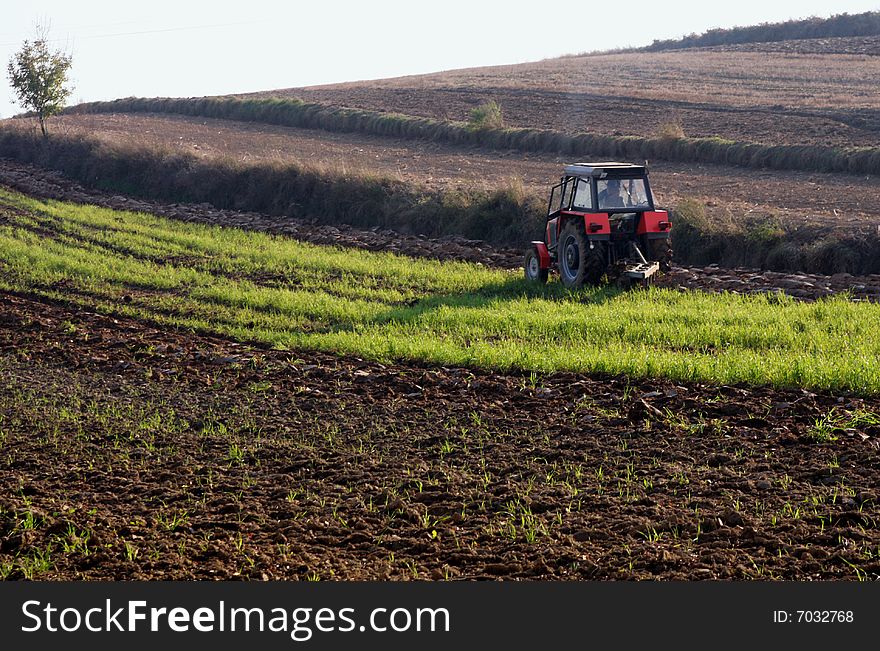 Red-black tractor working on a field