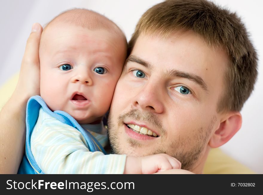 Baby embraced by its father. Both are lookling straight into camera. Baby embraced by its father. Both are lookling straight into camera.